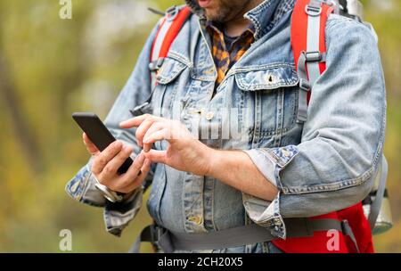 Cropped photo of a man using his smartphone like a navigator in a forest. Close up hands. Stock Photo