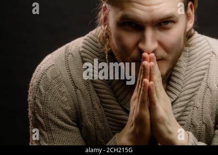 young handsome fair-haired man is holding hands in prayer and looking at the camera. close up cropped portrait Stock Photo