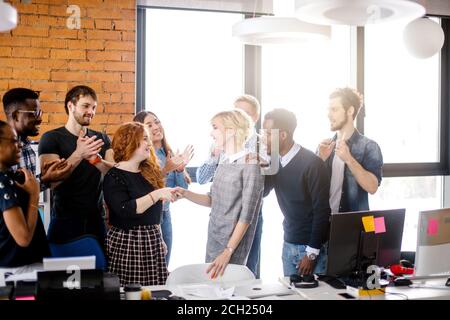 two workers are shaking hands after long enmity at work among happy employees Stock Photo
