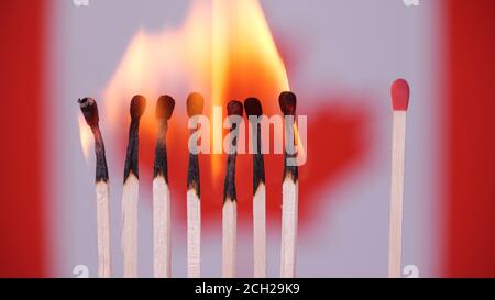 Coronavirus outbreak, social distancing concept. Burning matches on Canada flag background. Concept: spreading virus mechanism. COVID-19 Stock Photo