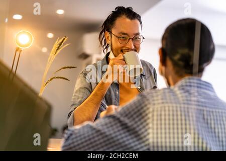 Two asian businessmen workers talking and discussion while coffee break bar at common zone of office. Office life concept. Stock Photo