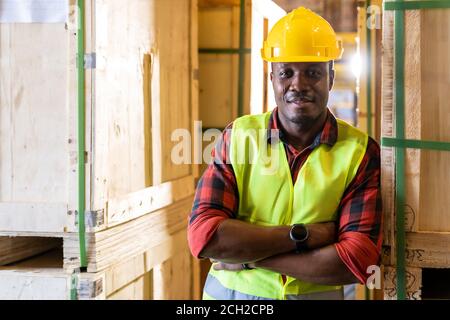 Portrait of african black warehouse worker standing and crossed his arms smile and looking at camera in large warehouse distribution center. Using in Stock Photo