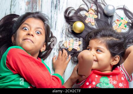 Smiling sisters decorating their hair with Christmas decorations Stock Photo