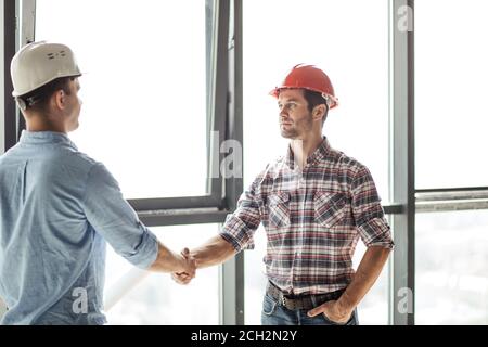 working partnership concept. architect is giving a hand to a n engineer to show his collaboration. close up portrait. builder has accepted the terms o Stock Photo