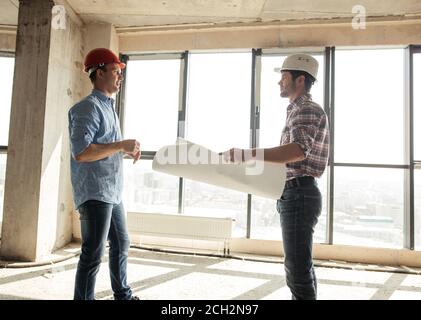 handsome client is discussing the project with a chief engineer in the building area. side view shot Stock Photo