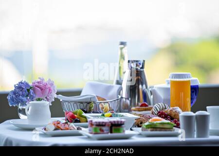 plates with assorted breakfast meal on a white table in a hotel room Stock Photo