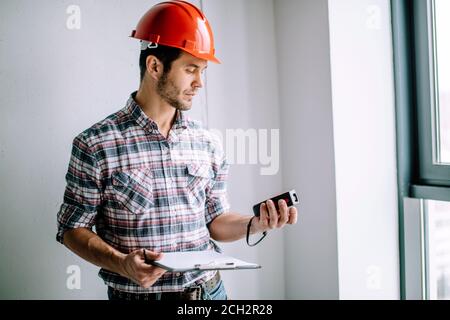 constructor is using the tape measure during work. close up side view photo. equipment concept Stock Photo