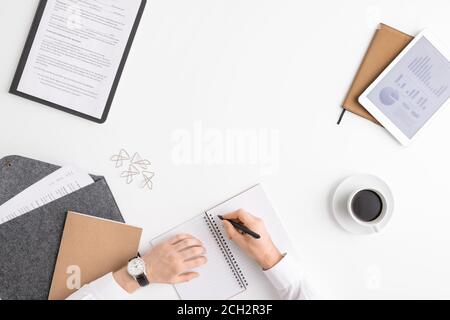 Overview of hands of young broker or economist with pen over blank page Stock Photo