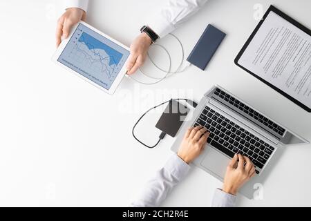 Top view of hands of two clinicians using mobile gadgets during work in hospital Stock Photo