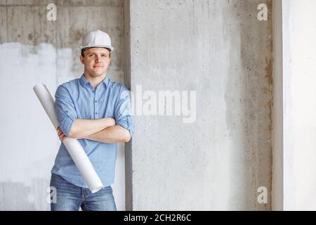 handsome supervisor with blueprint leaning on the wall of construction. copy space. close up portrait Stock Photo