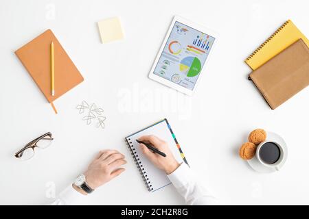 Overview of hands of young businessman holding pen over blank page of notebook Stock Photo