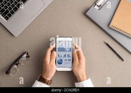 Flat layout of hands of young modern economist or accountant analyzing data Stock Photo