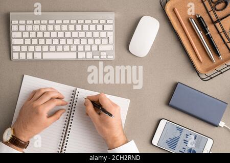 Flatlay of hands of elegant broker with pen over blank pages of open notebook Stock Photo