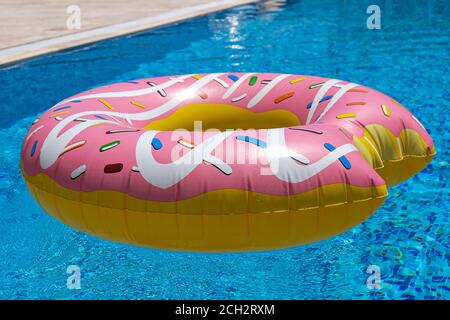 pink inflatable donut doughnut floating mattress in swimming pool. Beach pool accessories. Summer holiday concept Stock Photo