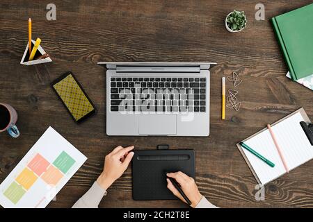 Overview of hands of young creative designer using stylus and graphic tablet Stock Photo