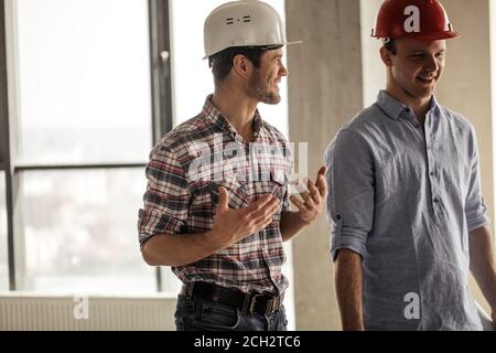 active positive engineers are having fun at workplace. positive workers in hardhats Stock Photo
