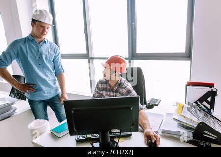 two ambitious construcors are studing the project from the computer in the office with modern interior. close up photo Stock Photo