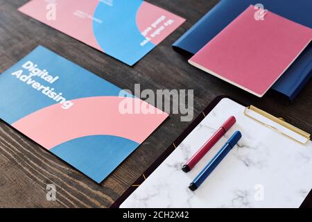 Two highlighters on paper in clipboard surrounded by brochures and copybook Stock Photo