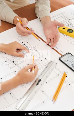 Hands of two young contemporary engineers discussing new sketches at meeting Stock Photo