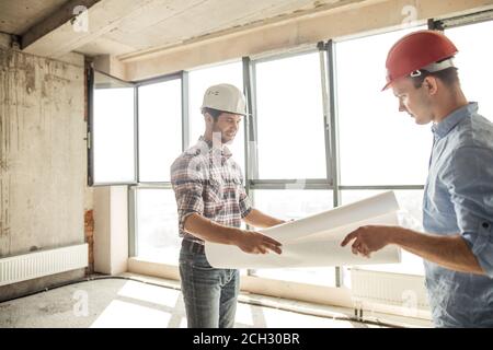 talented engineer is handing in a plan of construction to a chief. side view photo. panorama window on the background Stock Photo