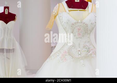 Beautiful haute-couture wedding dress with handmade intricate embroidery and crystal details on a mannequin in a bridal design workshop. Stock Photo