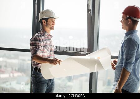 two positive architects are discussing the interior of a room in the working area. side view photo Stock Photo
