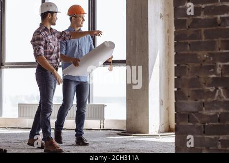 a positive engineer is boasting about new skyscraper to a colleague while walking in the construction area Stock Photo