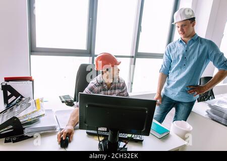 experiensed engineer is teaching a new colleague working on the computer. technology concept Stock Photo