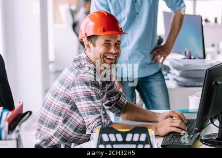 handsome cheerful engineer is having fun in front of the computer at work. happiness concept Stock Photo