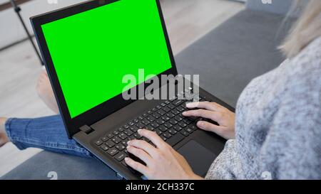 Woman using laptop with green screen. Woman typing on a laptop keyboard. Business, communication, freelance and internet concept Stock Photo