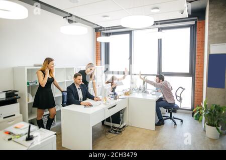 good job of computer designers. happy two programmers giving five to each other while their colleagues preparing documents Stock Photo