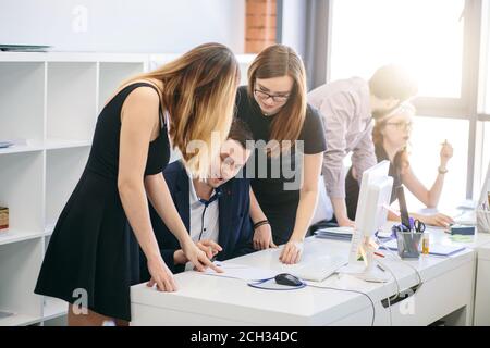 two cunning women are forcing their boss to sign the document in the modern office. Stock Photo