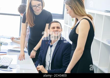 CEO is flirting with pleasant female offfice workers. smiling inspector is sitting between elegant employees. close up cropped photo. Stock Photo