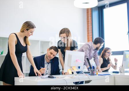 handsome auditor in suit is checking the work of small firm in the loft office Stock Photo