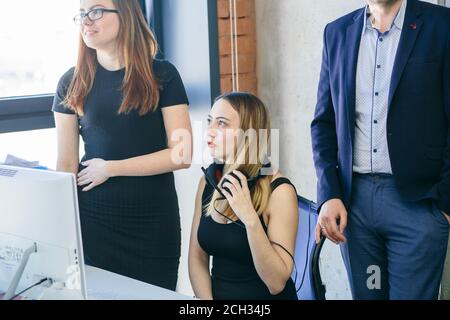 close up cropped photo of two female operators in black dresses and man in suit at work Stock Photo