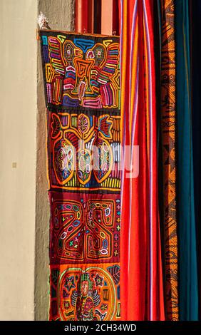 Panama City, Panama - November 30, 2008: Vibrant colors on indigenous band of textile as decoration against downtown light yellow wall. Stock Photo