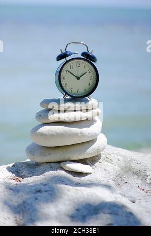 ALARM CLOCK AT THE BEACH ON BALANCING ROCKS. CONCEPT OF MEDITATION AND ZEN TIME AT THE BEACH Stock Photo