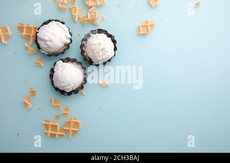 Top view of vanilla ice cream balls in waffle and chocolate bowl on blue background Stock Photo