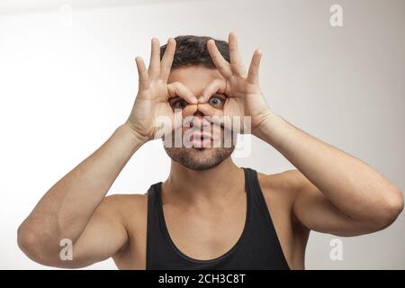 funny man is looking through glasses from fingers Stock Photo