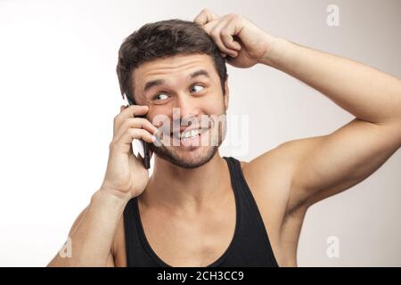 young male in undershirt is scratching his hear as he is thinking about the information.man with alluring proposal. attractive idea, offer Stock Photo