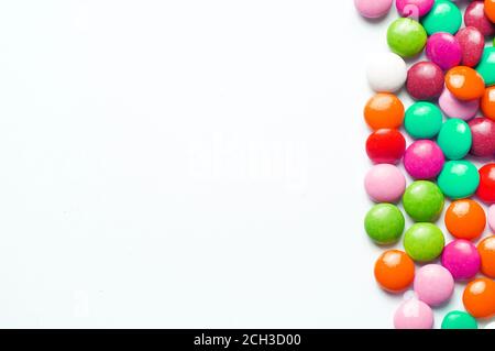Colored balls of sugar on a white background. Chocolate candies covered with multicolored sugar glaze. Place for text Stock Photo