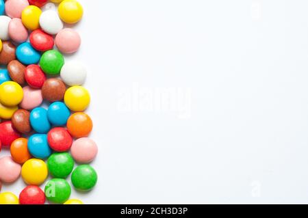Colored balls of sugar on a white background. Chocolate candies covered with multicolored sugar glaze. Place for text Stock Photo