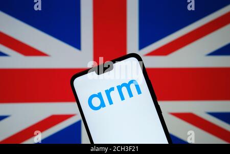 ARM Holdings logo seen on the silhouette of smartphone hold in hand and the United Kingdom flag on a blurred background Stock Photo