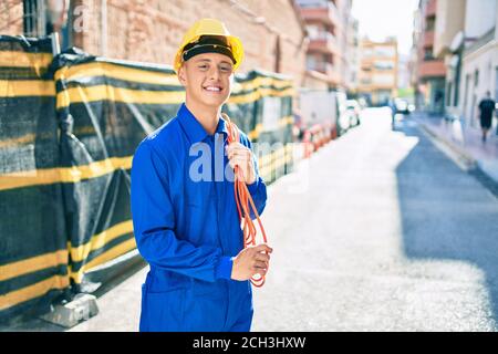 Young hispanic workman smiling happy holding electrical cable at street of city Stock Photo