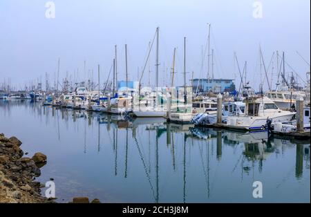 El Granada, California USA - September 12, 2020: Boats docked at the fishing pier in Half Moon Bay near San Francisco with fog over the Pacific Ocean Stock Photo