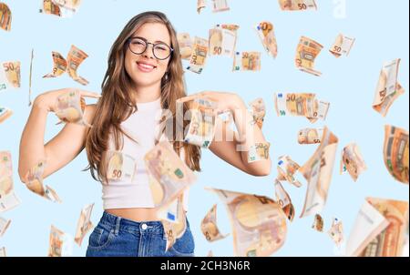 Beautiful caucasian young woman wearing casual clothes and glasses looking confident with smile on face, pointing oneself with fingers proud and happy Stock Photo