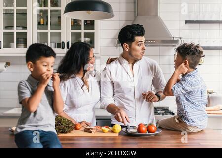 Family making funny faces at each other while preparing lunch meal