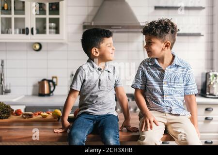 Two boys on stylish kitchen counter making funny faces at each other
