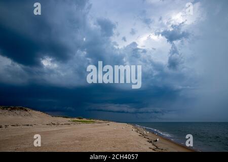 Dark storm clouds rising above vacant sandy beach. Stock Photo