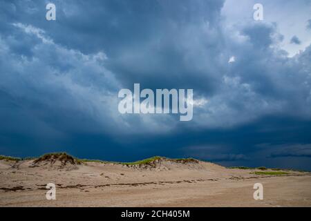 Dark storm clouds rising above vacant sandy beach. Stock Photo